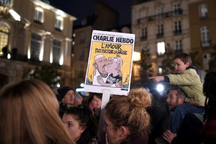 Atentat terorist în Franţa. O femeie ridică o pancartă conţinând una dintre caricaturile reprezentative pentru profilul publicaţiei "Charlie Hebdo" în timpul unui miting de susţinere FOTO bostonglobe.com