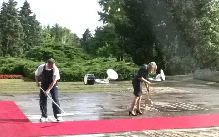 Din cauza ploii, angajaţii Administraţiei Prezidenţiale croate au scos teuri de lemn şi au îndepărtat apa de pe covorul rosu. Chiar şi o doamnă îmbrăcată în ţinută office, purtând pantofi cu toc, a pus mâna pe mătură şi a muncit cot la cot cu bărbaţii. Foto Sebastian Zachmann