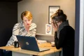 doua femei citesc informatii de pe laptop jpg
