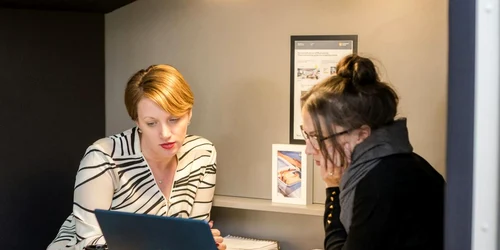 doua femei citesc informatii de pe laptop jpg