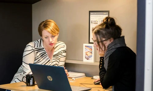 doua femei citesc informatii de pe laptop jpg