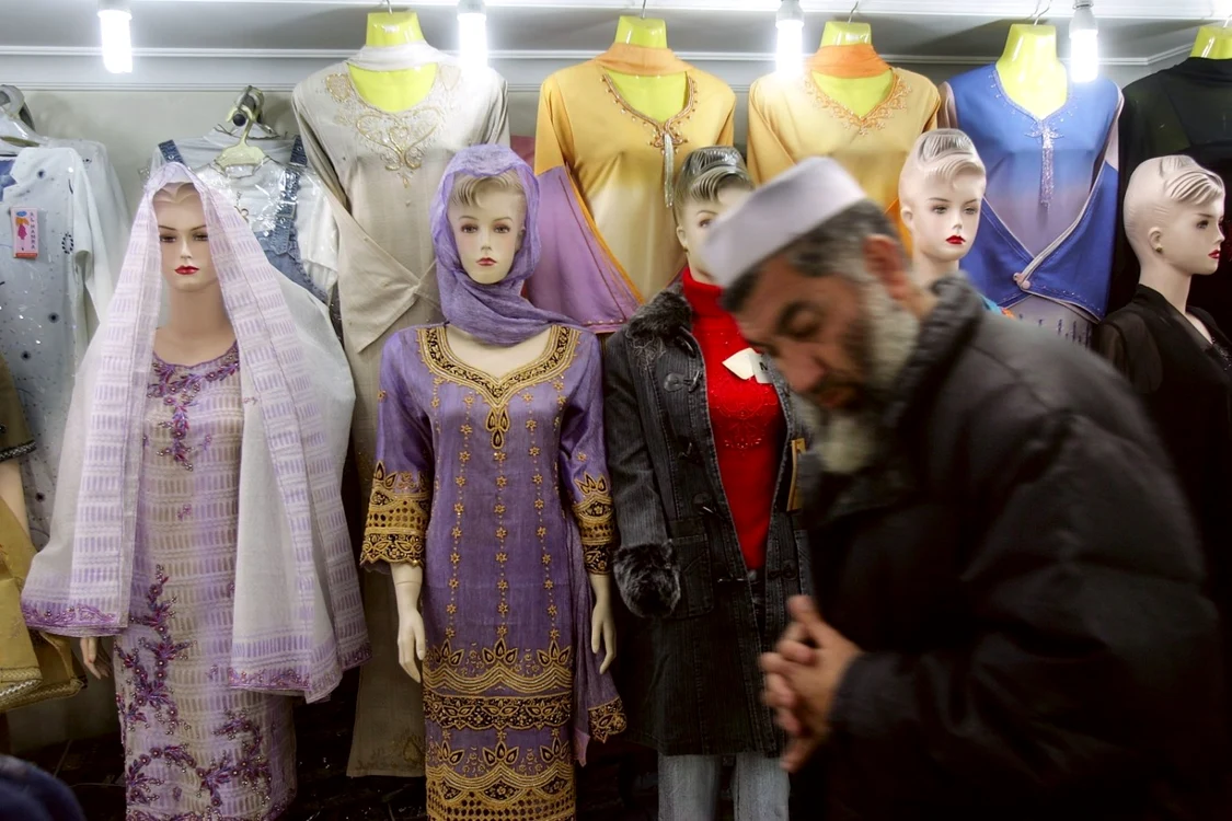 FOTO: Getty Images / Un afgan îşi fereşte privirea în timp ce trece pe lângă manechine, în centrul comercial Kabul City Center, 8 februarie 2006
