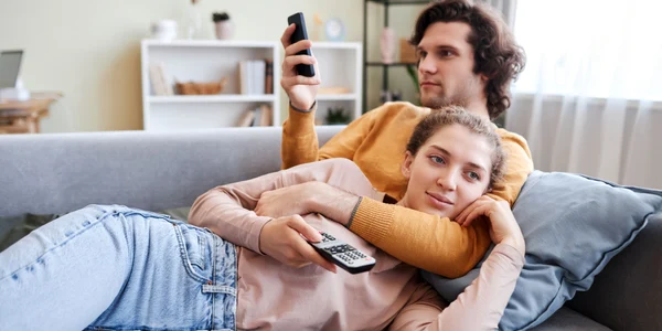 Cuplu care stă la TV și se uită pe telefon FOTO Shutterstock