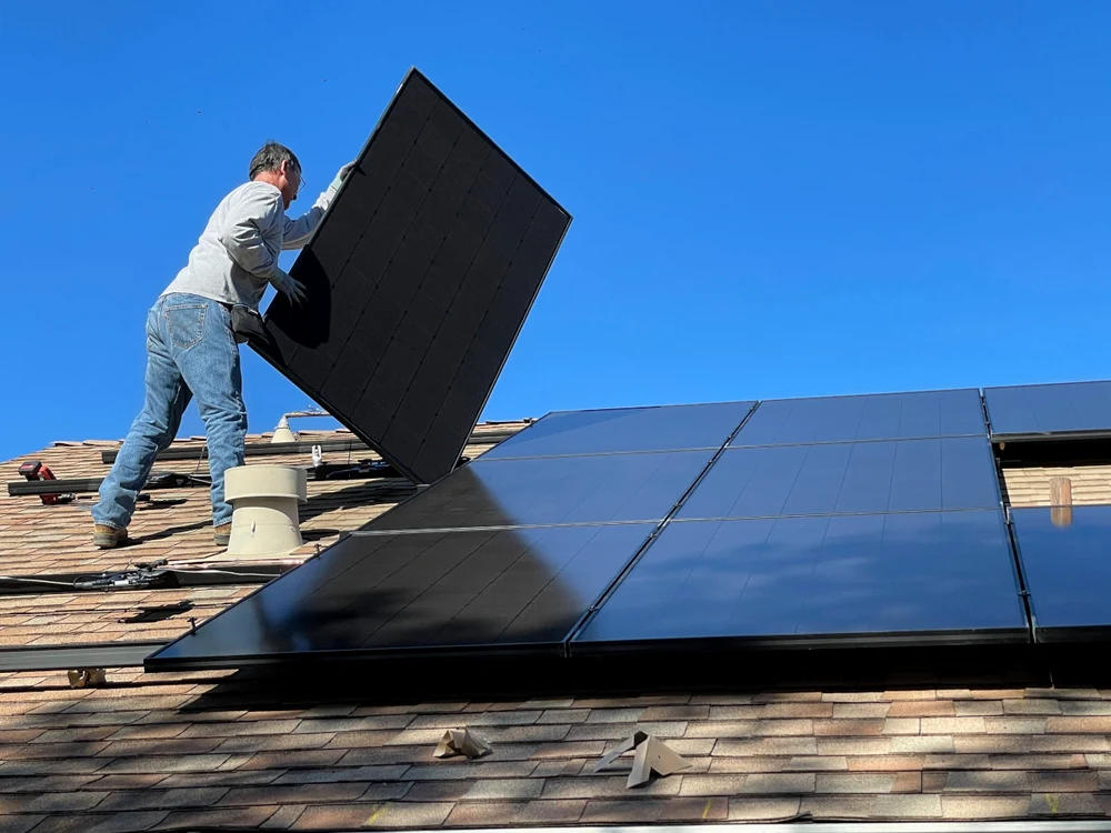 Un instalator montează panouri fotovoltaice pe un acoperiș