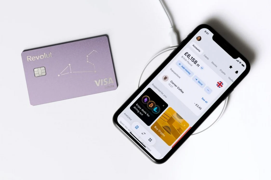 Card Revolut lângă un telefon pe care este deschisă aplicația