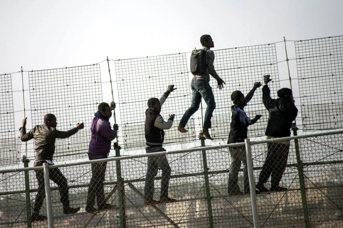 Imigranţi africani încercând să treacă de garduri. FOTO: Reuters