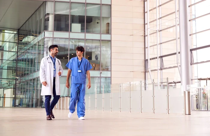 Un medic și un asistent discută în timp ce merg
