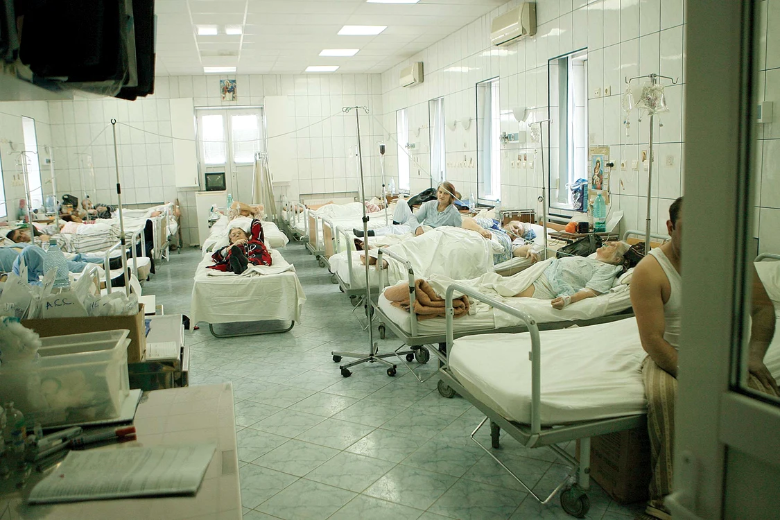 În salonul alăturat, bolnavii zac în paturi și așteaptă supa de prânz