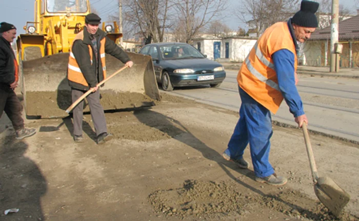 Muncitorii astupă cu pământ gropile de pe străzi