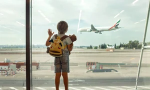 Copil in aeroport cu bagaje -avion pe fundal FOTO Shutterstock 