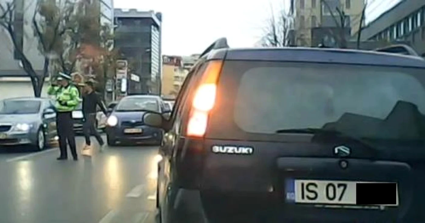 Poliţistul vorbeşte la telefon în timp ce un pieton traversează neregulamentar