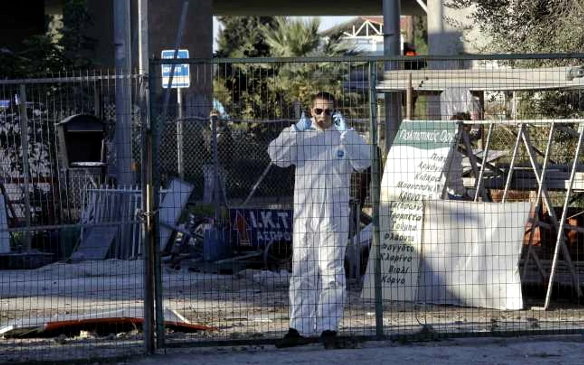 Un parlamentar, membru al partidului extremist de dreapta Zorii de Aur, îmbrăcat într-o uniformă de protecţia, stând de vorbă în faţa filialei locale a partidului, situată în suburbia de vest a Atenei, unde a explodat marţi o bombă FOTO Reuters