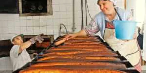Nicolae Şchiopotă scoate din cuptor cozonacii care sunt unşi de ajutoarele din brutărie