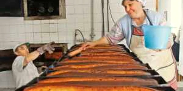 Nicolae Şchiopotă scoate din cuptor cozonacii care sunt unşi de ajutoarele din brutărie
