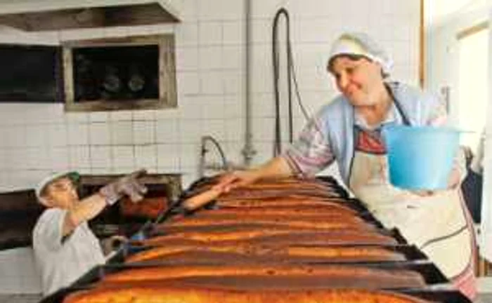 Nicolae Şchiopotă scoate din cuptor cozonacii care sunt unşi de ajutoarele din brutărie
