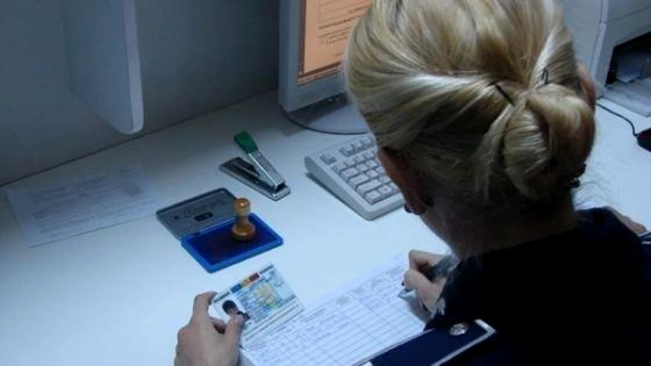 O polițistă scrie datele dintr-un buletin de identitate într-un registru