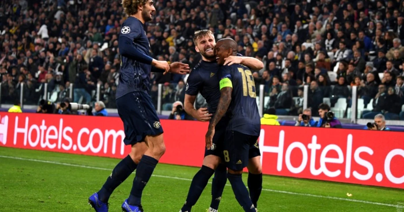 Trei jucători de fotbal de la Manchester United se îmbrățișează pe teren