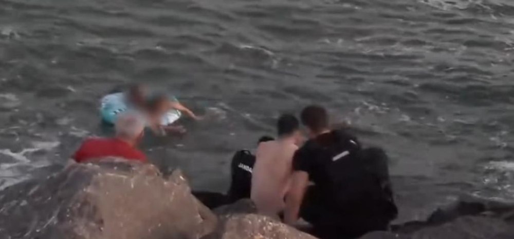 Momentul în care două persoane cu un colac, purtate de valuri în larg, au fost recuperate din mare la Constanța