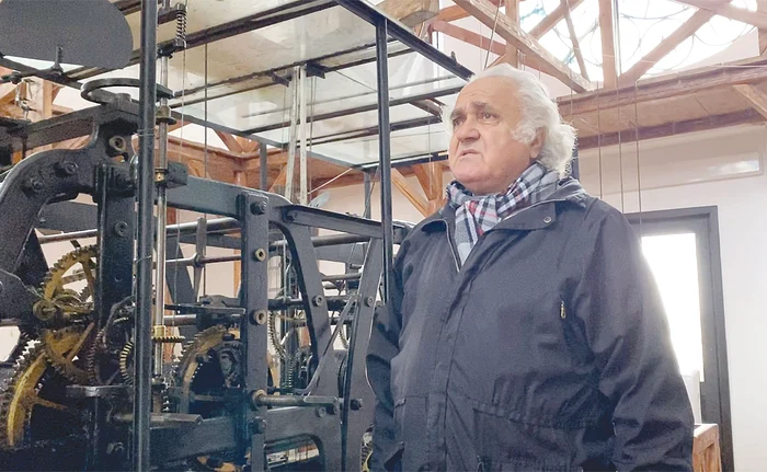 Ion Cristea, lângă o parte din mecanismul complex al orologiului. Foto: “Weekend Adevărul”