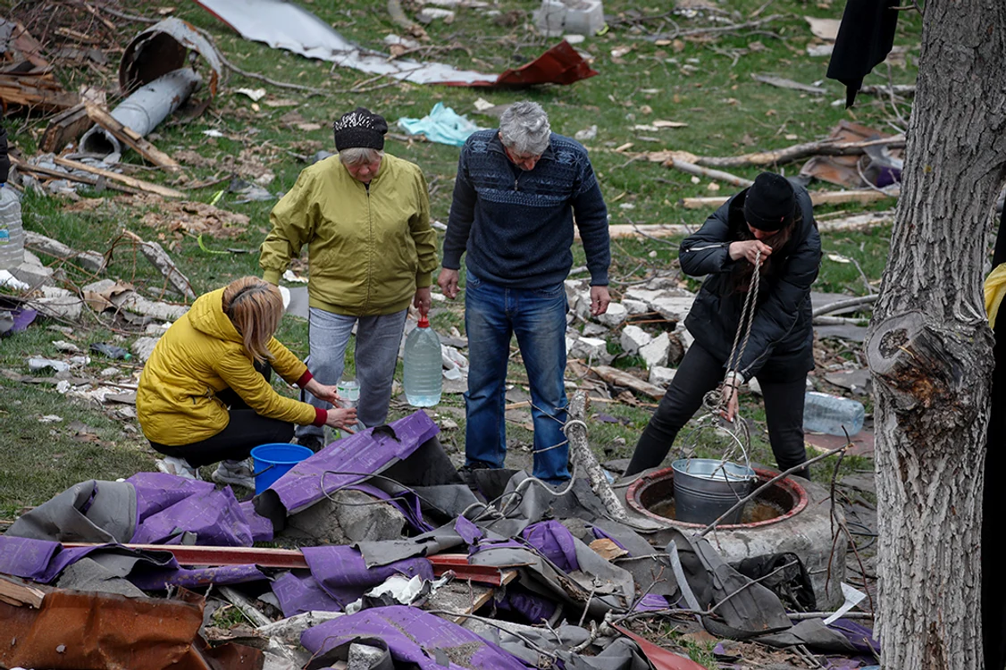 Sinistrații, obligați să se  expună gloanțelor pentru  a duce apă în buncăr. Fotografii: EPA - EFE