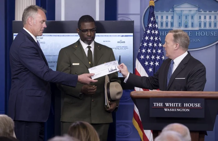 Sean Spicer (dreapta), purtătorul de cuvânt al Casei Albe, i-a înmânat cecul cu donaţia preşedintelui Donald Trump secretarului american de Interne, Ryan Zinke (stânga) Foto: EPA