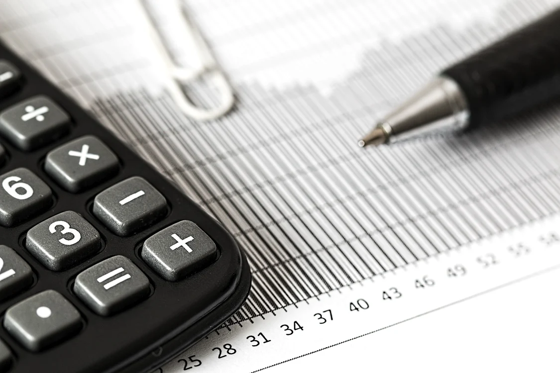 Un calculator pus pe o hârtie gradată pe care este și un pix negru