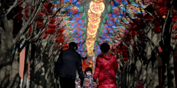 Un cuplu ţine un copil în picioare pe un scuter în timp ce trec pe sub decoraţiuni colorate pentru un târg înainte de Anul Nou Chinezesc în parcul Ditan de la Beijing China FOTO AP