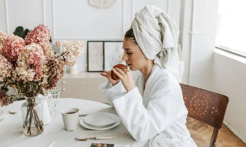 femeie ia micul dejun acasa vaza flori ziar croissant dupa dusul de dimineata 5357432 jpg