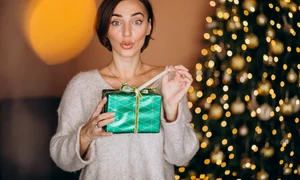 young woman with christmas present by christmas tree (1) jpg