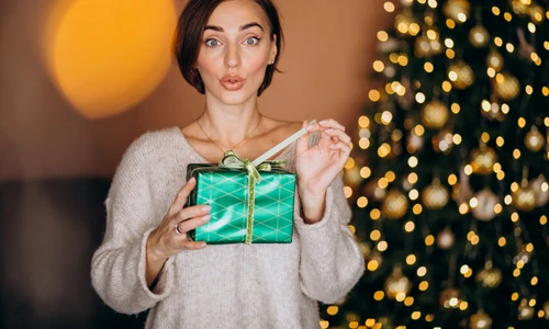 young woman with christmas present by christmas tree (1) jpg
