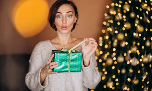 young woman with christmas present by christmas tree (1) jpg