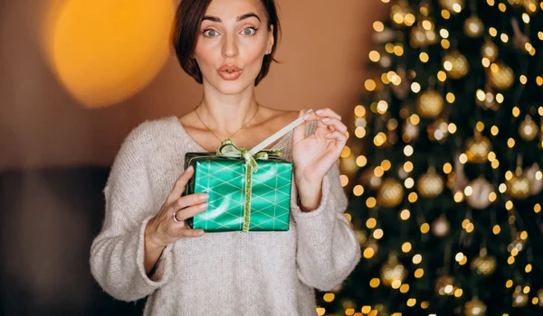 young woman with christmas present by christmas tree (1) jpg
