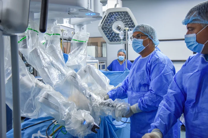 Medici în sala de operație efectuând o operație prin chirurgie robotică
