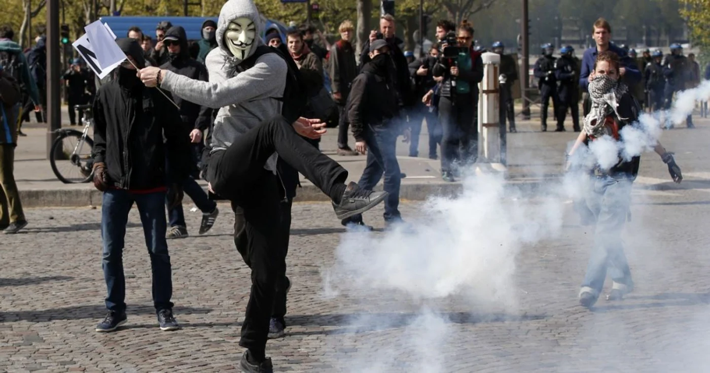 Un protestatar mascat loveşte cu piciorul un recipient cu gaz lacrimogen în timpul protestelor  din Paris contra reformei legii muncii din Franţa. joi, 28 aprilie 2016. FOTO AP