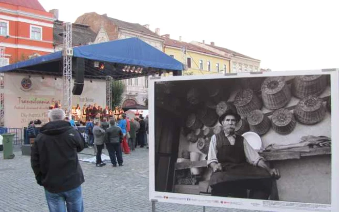 Câţiva zeci de clujeni au participat la deschiderea Festivalului Transilvania Fest. Unii admirau fotografiile cu meşteşugari  - cum este cea cu împletitorul de coşuri - expuse în Piaţa Unirii  FOTO: Florina Pop