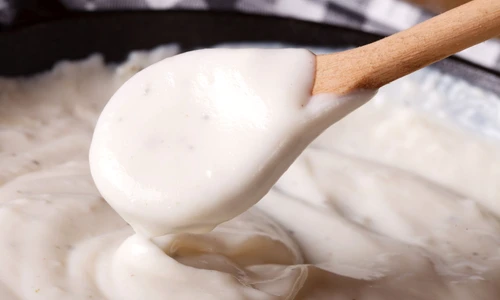 bechamel sauce with a wooden spoon close up, horizontal jpeg