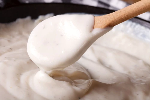 bechamel sauce with a wooden spoon close up, horizontal jpeg