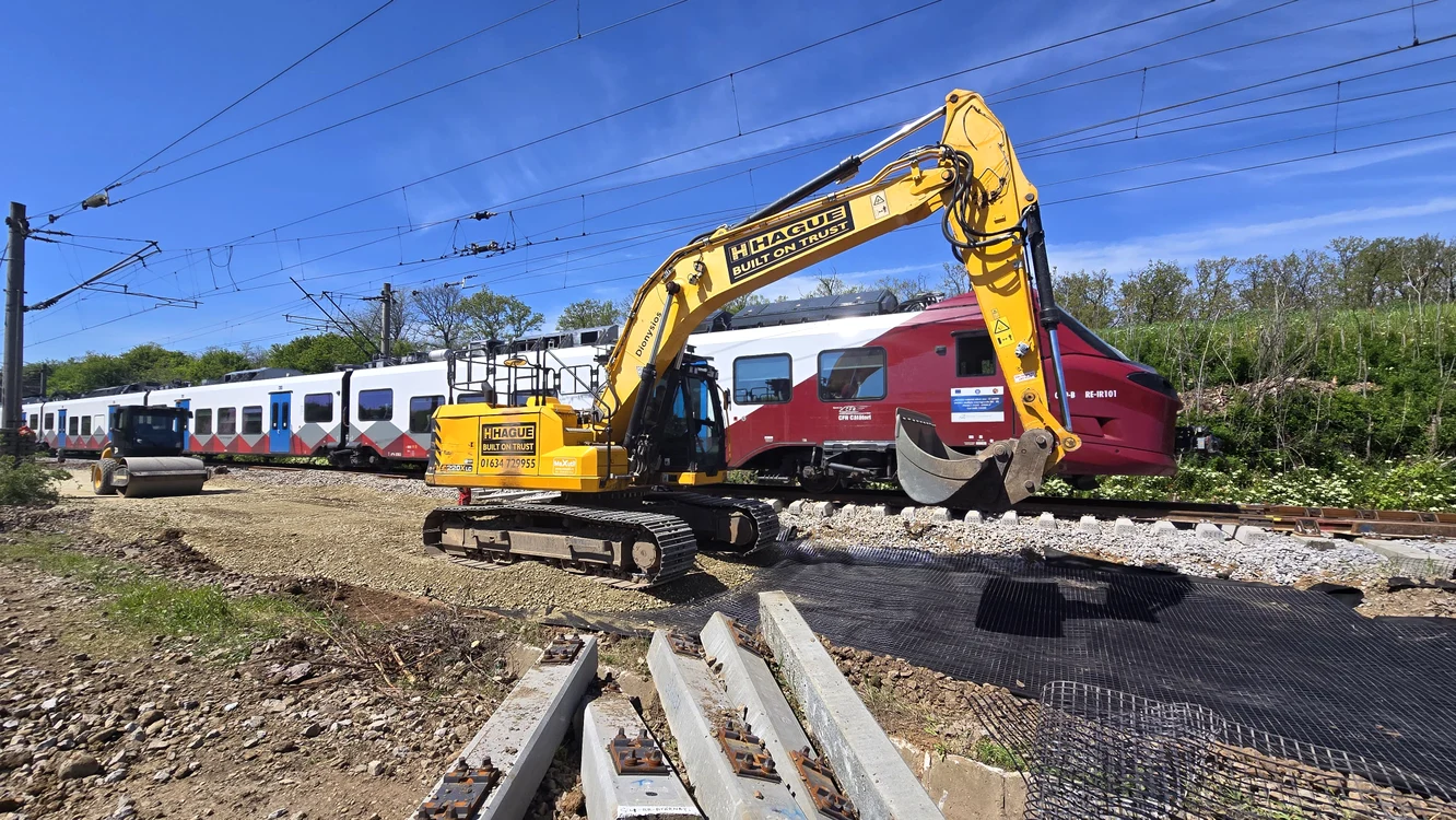 Lucrări de modernizare a căii ferate, lângă un tren care staționează