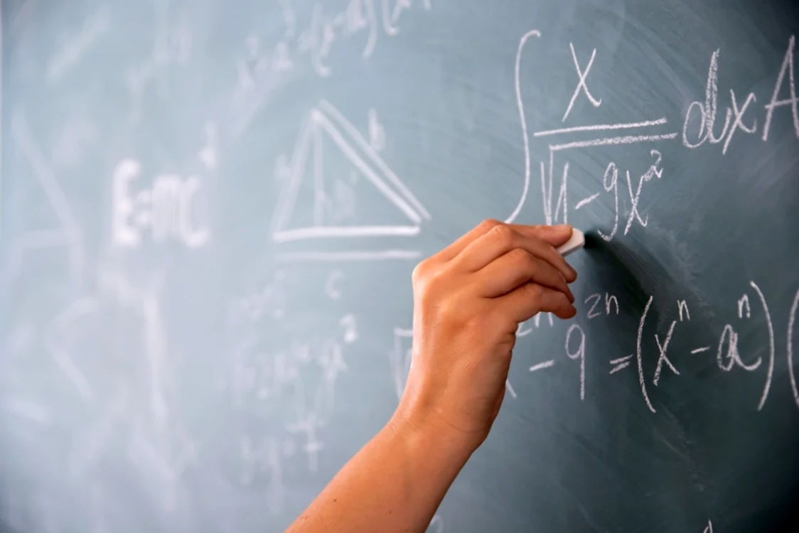 Mana de profesor care rezolva o problema de matematica cu creta pe tabla