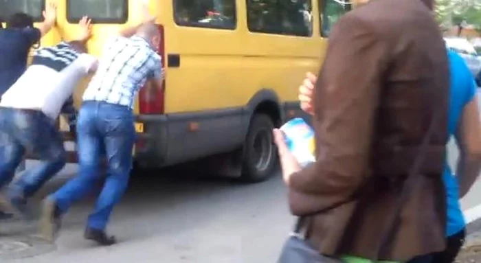 Câţiva tinri cu muşchi au fost de acord să pună în mişcare microbuzul blocat pe şosea. Foto: Captură YouTube
