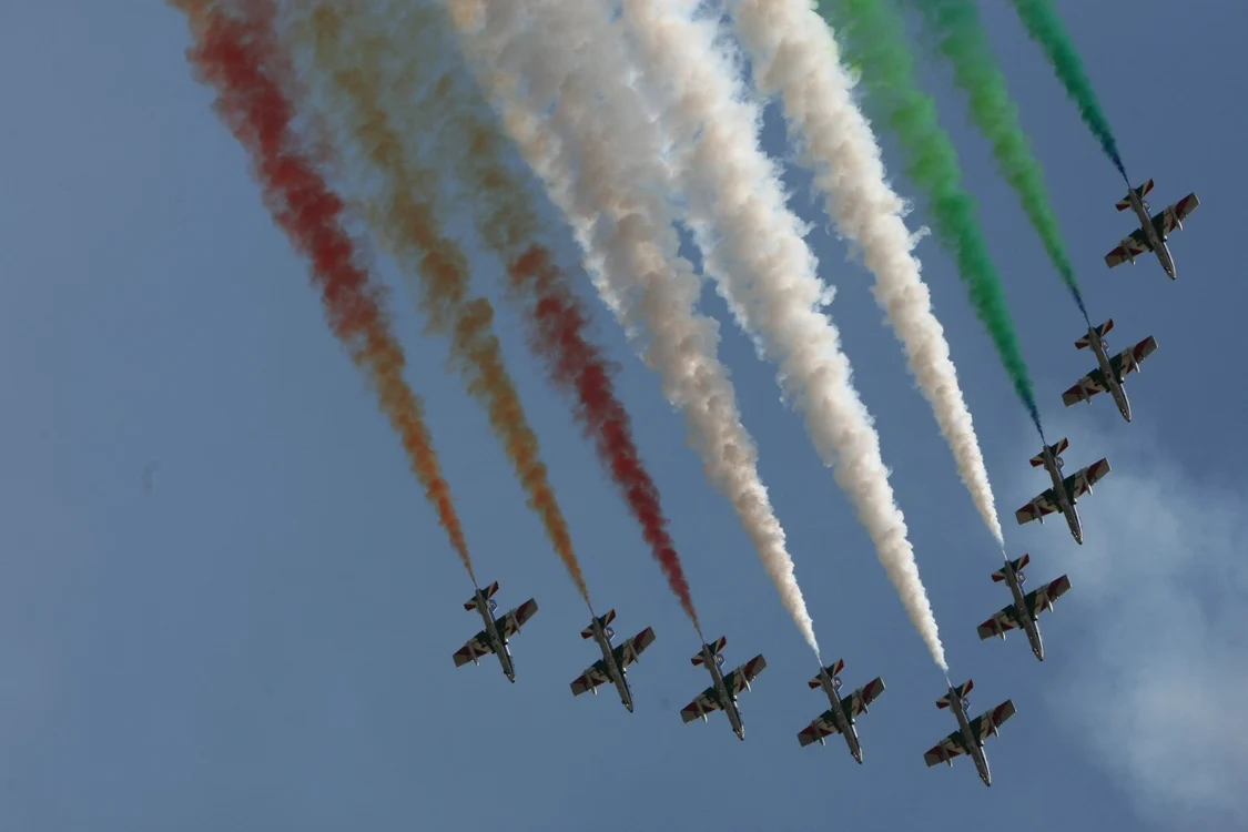 Formațiune de avioane pe cer, care lasă în urmă dâre colorate la un show aviatic