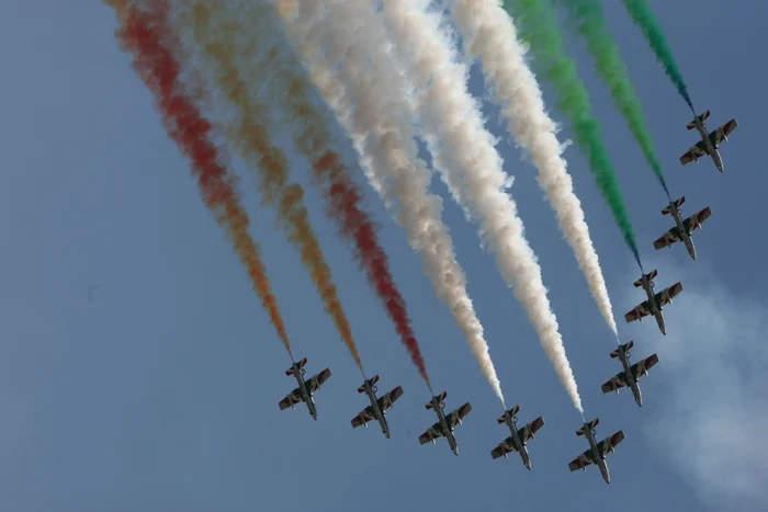 Formațiune de avioane pe cer, care lasă în urmă dâre colorate la un show aviatic