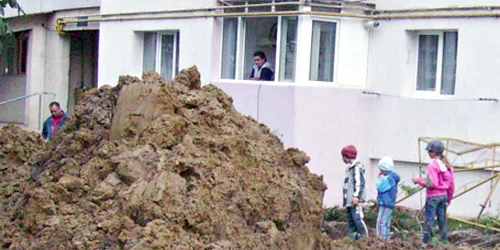 Copiii se joacă printre şanţurile săpate de muncitori pentru înlocuirea conductelor de apă şi canalizare