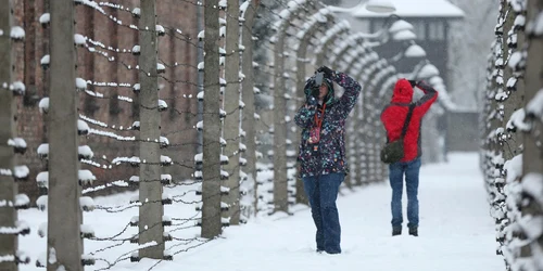 Vizitatori fac fotografii între gardurile de sârmă  ghimpată care înconjoară fostul lagăr de la  Auschwitz care în prezent este muzeu în Oswiecim Polonia FOTO Guliver/Getty Images