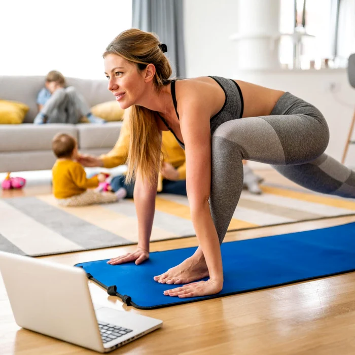 Femeie care face fitness digital acasă, lângă familie Foto Shutterstock