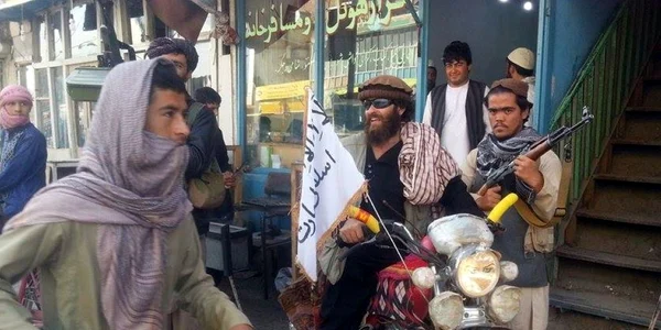 Un luptător stă pe motocicleta în care e înfipt un steag Taliban pe o stradă din oraşul Kunduz Afganistan FOTO AP
