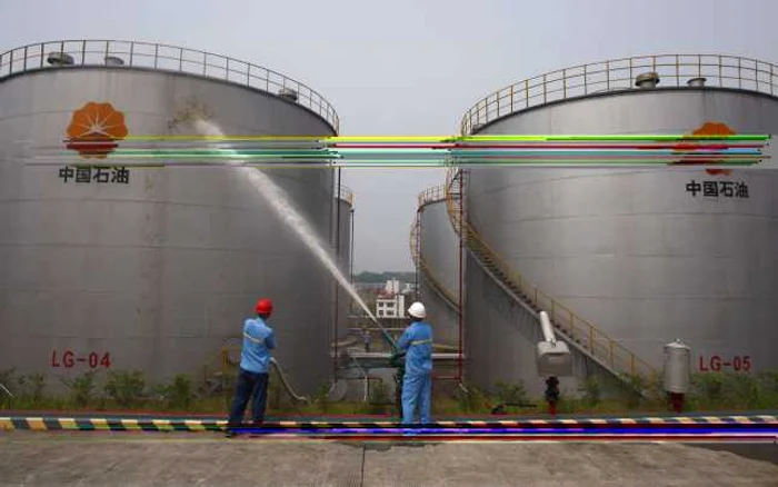 Lucrători ai companiei PetroChina, lucrând în apropierea a două rezervoare. FOTO: Reuters