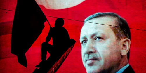 Un susţinător al preşedintelui turc Recep Tayyip Erdogan cu un steag e fotografiat în dreptul unui panou electronicîn timpul unui miting din Piaţa Kizilay la Ankara Turcia FOTO Guliver/ Getty Images / Chris McGrath