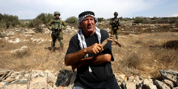 Soldaţi israelieni stau lângă un fermier palestinian care aşteaptă să ajungă la o fermă pentru a culege măsline la marginea satului Yetma din Cisiordania lângă aşezarea evreiască Rehelim FOTO EPA-EFE / Alaa Badarneh
