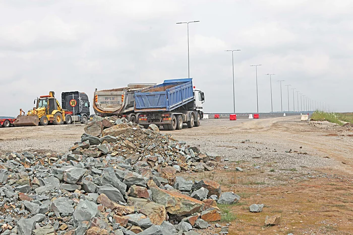 Munţi de pietre stau în faţa drumului finalizat